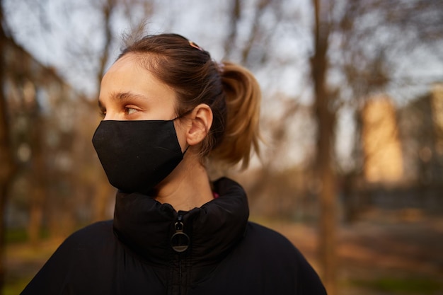 fille dans un masque médical noir dans la rue quarantaine auto-isolement