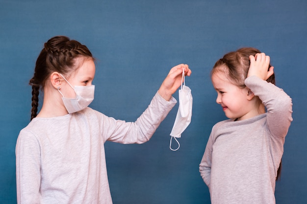 Une Fille Dans Un Masque Médical Suggère De Porter Un Masque Propre à Une Autre Fille. Protection De L'enfance