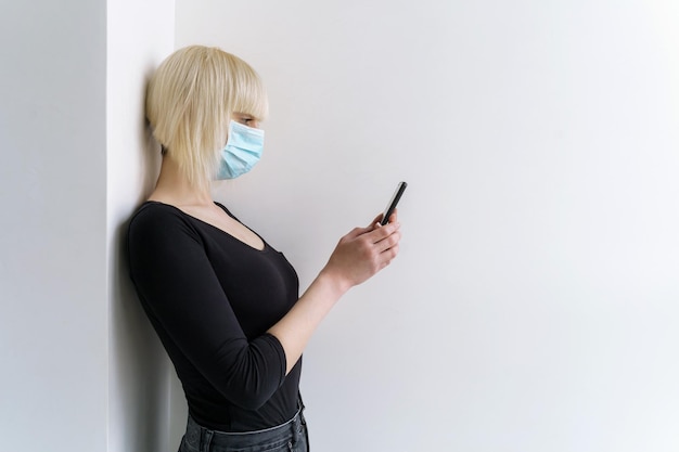 Une fille dans un masque médical tenant un téléphone portable