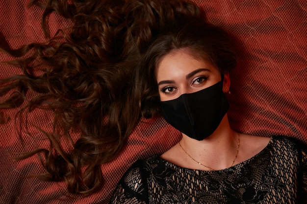 Une Fille Dans Un Masque Noir Est Allongée Sur Le Lit