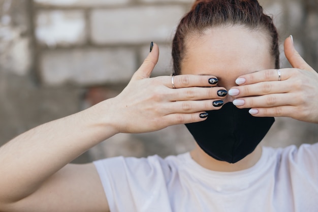 Une fille dans un masque de protection couvre ses yeux avec ses mains