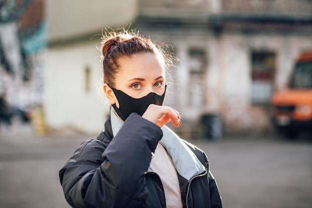 Une fille dans un masque de protection touche son visage