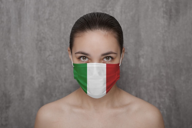 Une fille dans un masque sur son visage avec le drapeau de l'Italie