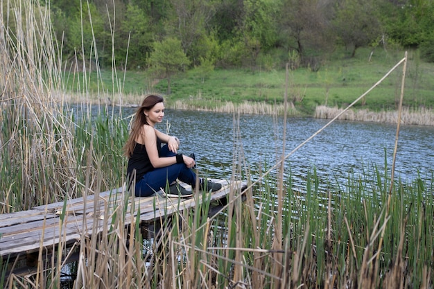 Photo fille dans la nature assis au bord de l'eau