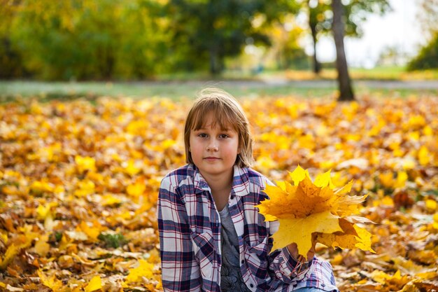 Fille dans le parc d'automne avec un bouquet de feuilles jaunes