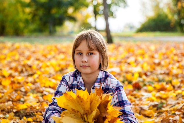 Fille dans le parc d'automne avec un bouquet de feuilles jaunes