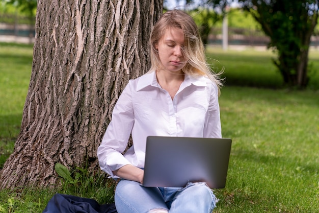 Une fille dans un parc de campagne est assise sur l'herbe verte