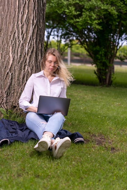 Une fille dans un parc de campagne est assise sur l'herbe verte