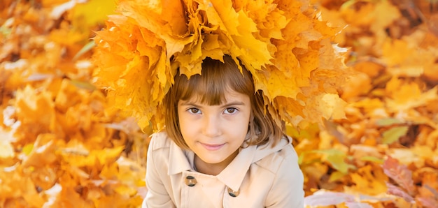 Fille dans le parc avec des feuilles d'automne.