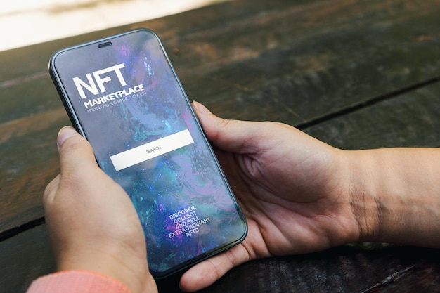Fille dans le parc tenant un smartphone avec l'application NFT NonFungible Token Marketplace sur l'écran Table en bois rustique