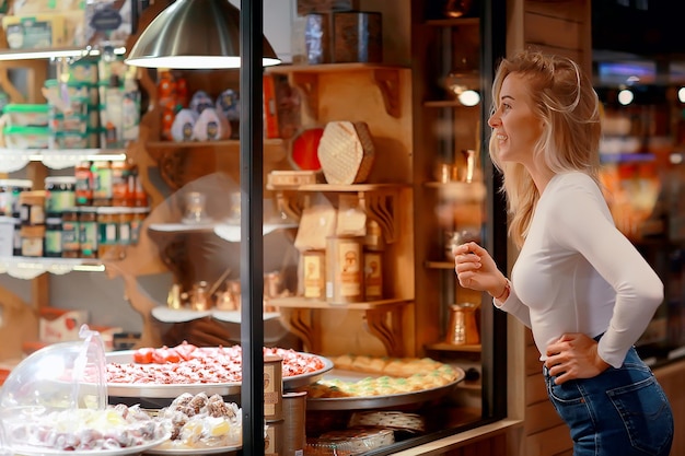 fille dans une pâtisserie, délicieuse nourriture sucrée, une jeune femme adulte se tient à la fenêtre