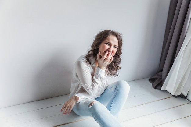 Fille dans une pièce lumineuse assise contre un mur blanc