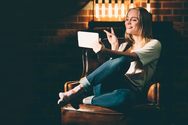 Fille dans une pièce sombre confortable tenant la tablette