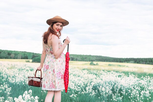 Fille dans une prairie d'été avec une fleur blanche par temps nuageux