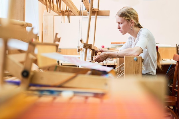 La fille dans le processus de production de textiles est faite à la main sur un métier à tisser