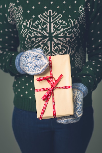 Une fille dans un pull du Nouvel An tient un cadeau.