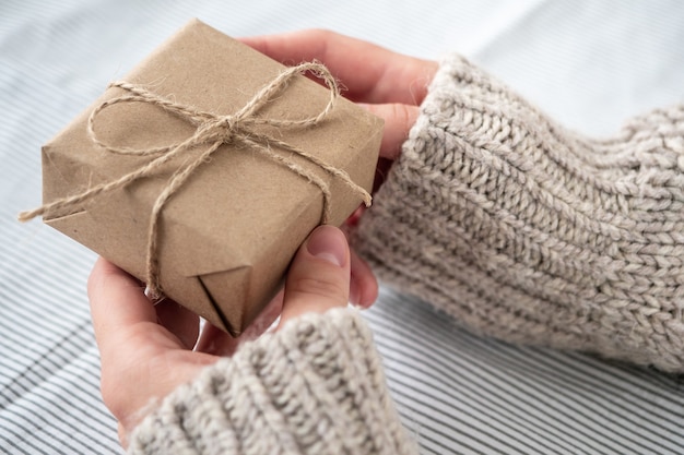 Une fille dans un pull est titulaire d'un cadeau décoré de ses propres mains. Magnifique coffret cadeau en papier Kraft