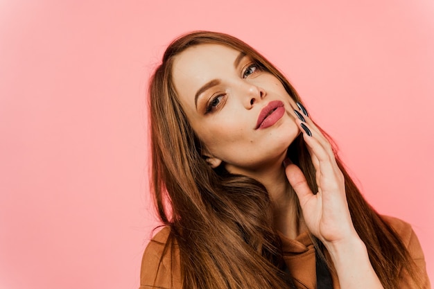 Fille dans un pull marron sur fond rose