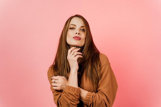 Fille dans un pull marron sur fond rose