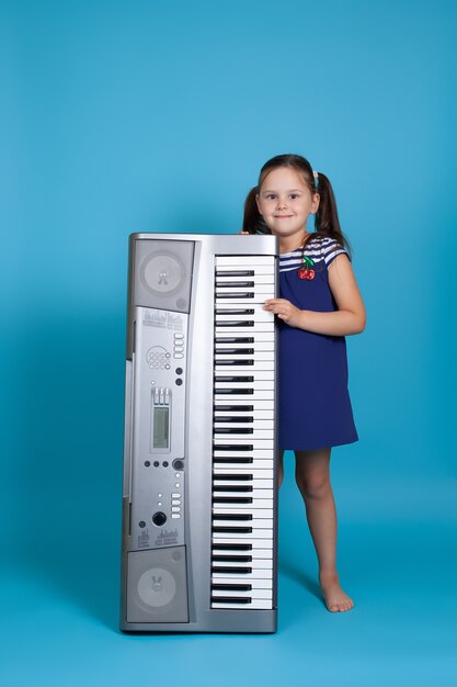 fille dans une robe bleue tient un synthétiseur électronique vertical