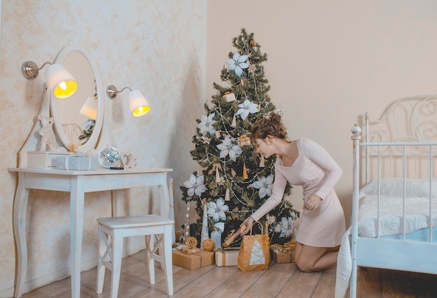 Une fille dans une robe d'été beige le réveillon du nouvel an analyse les cadeaux