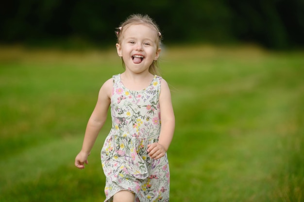 Une fille dans une robe d'été qui traverse le champ en été avec sa langue pendante et nat