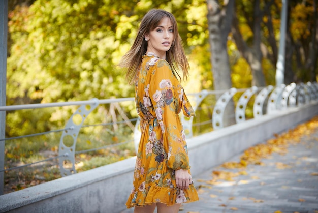 Une fille dans une robe jaune dans la perspective d'un parc d'automne