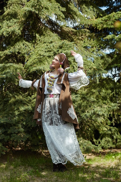 Fille dans une robe à la main de mode ethnique vintage posant à l'extérieur.