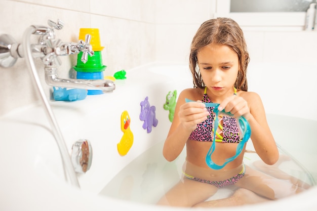 Une fille dans la salle de bain porte des lunettes de natation