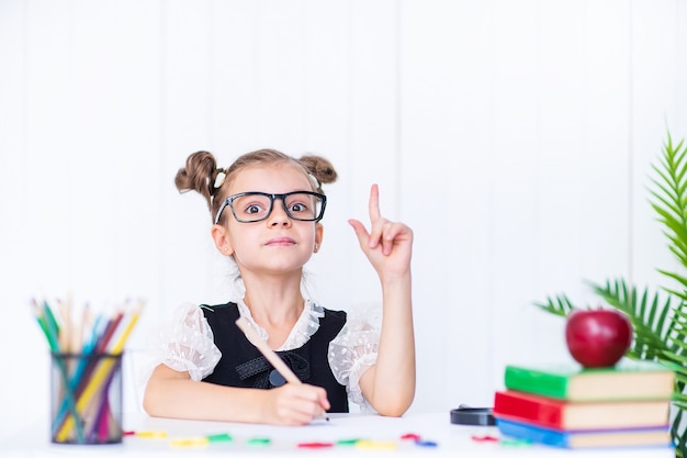 Fille dans la salle de classe avec des crayons et des livres