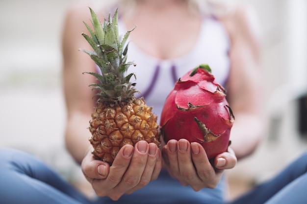 La fille dans la salle de gym tient des fruits exotiques dans ses mains