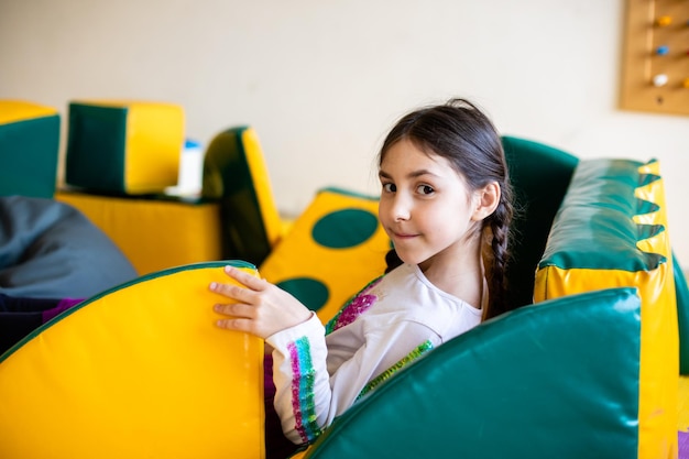 La fille dans la salle de jeux est assise sur des blocs mous