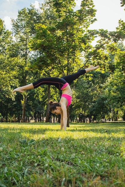 fille dans un survêtement léger faisant du yoga dans le parc dans l'après-midi en été