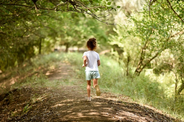 Une fille dans un T-shirt blanc court sous les arbres Nature Backgroung Belle