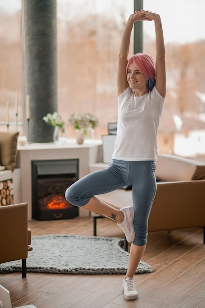 Une fille dans un t-shirt blanc debout dans une pose d'arbre