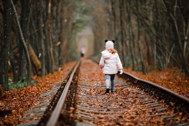 Fille dans le tunnel vert ferroviaire. tunnel d'amour en automne. Chemin de fer et tunnel d'arbres