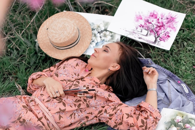 Une fille dans un verger de pêchers en fleurs se repose sous un arbre et une vue de dessus souriante