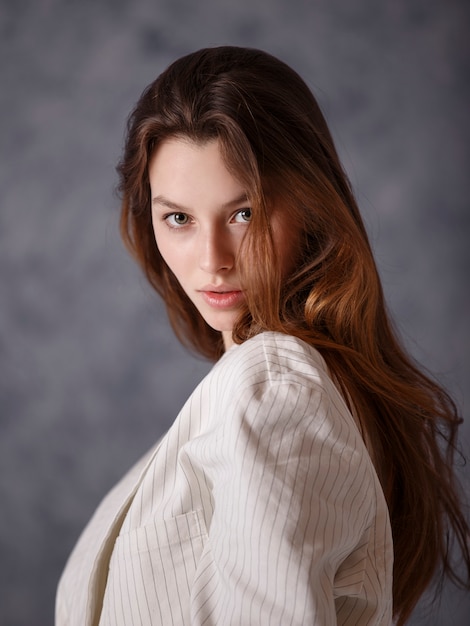 Fille dans une veste blanche sur fond gris