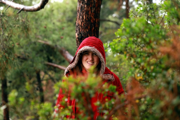 Une fille dans une veste à capuche rouge posant dans la forêt