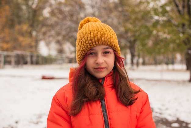 Une fille dans une veste chaude orange vif. Fille dans une veste orange par temps de neige. Adolescente en hiver