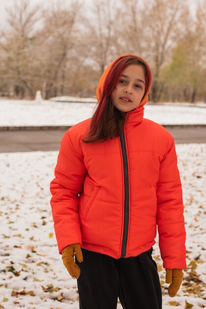 Une fille dans une veste chaude orange vif. Fille dans une veste orange par temps de neige. Adolescente en hiver