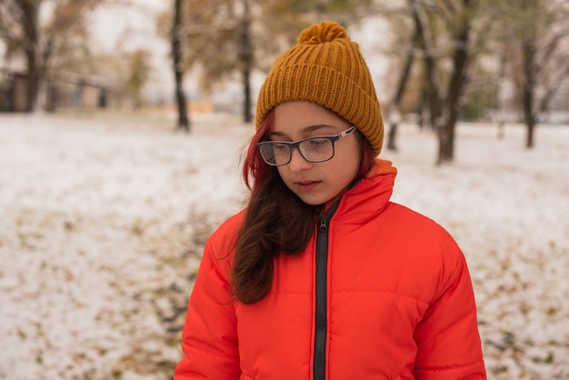 Une fille dans une veste chaude orange vif. Fille dans une veste orange par temps de neige. Adolescente en hiver