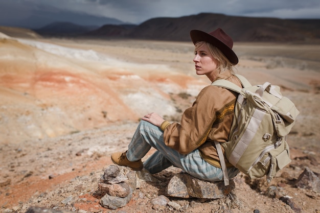 Photo fille dans une veste en cuir assise sur un rocher