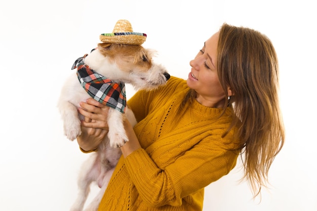 Une fille dans une veste jaune tient un chiot Jack Russell Terrier dans un chapeau et un bandana. Isoler sur fond blanc