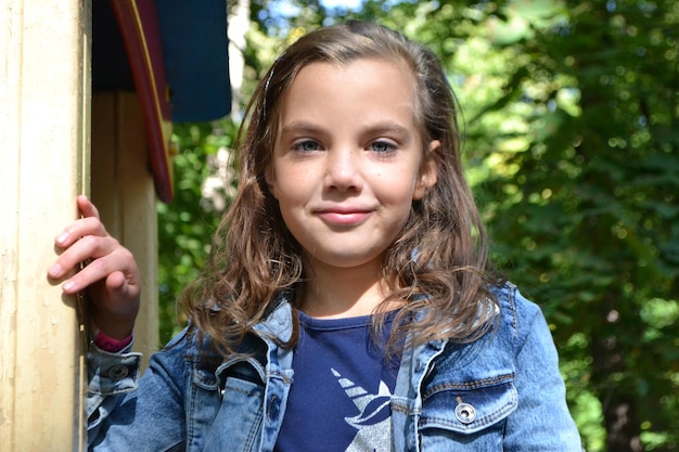 Une fille dans une veste en jean pose pour une photo.