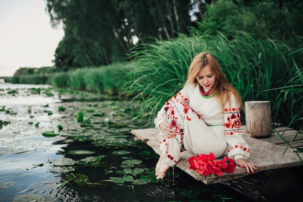 fille dans des vêtements traditionnels ukrainiens, assis au bord de l&#39;eau