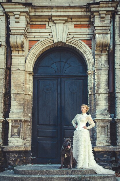 Fille dans une vieille robe à volants et un gros chien noir