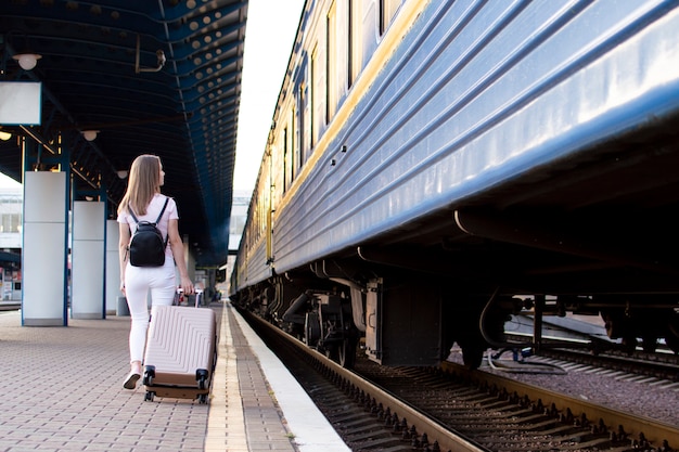 Fille debout avec des bagages à la gare