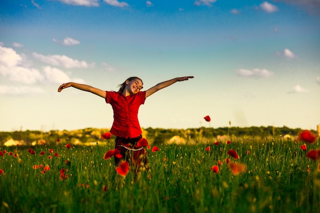 Fille debout avec les bras tendus dans le champ de coquelicots et profiter de la nature