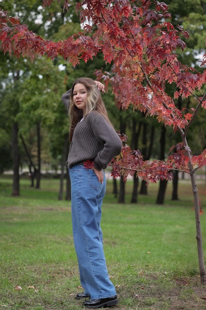 fille debout dans le parc et tenant sa main dans sa poche arrière